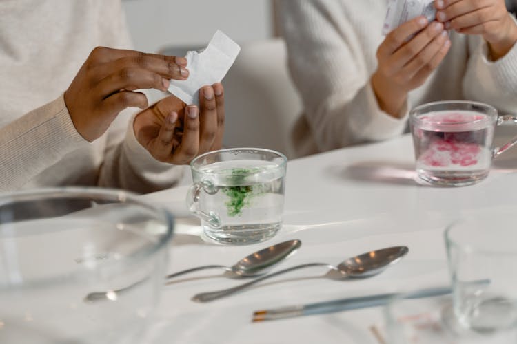 A Person Holding White Pack Near A Mug Of Water