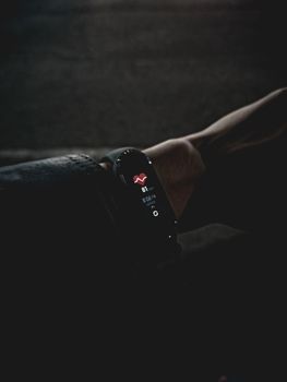 A close-up image of a fitness tracker displaying vital signs on a person's wrist in low light conditions.