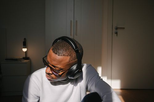 Free African American man enjoying music on headphones in a cozy indoor setting. Stock Photo