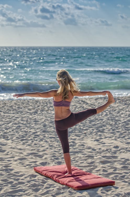 Mulher fazendo yoga na praia