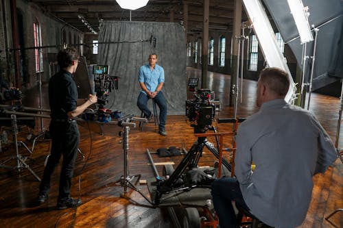 Free Behind the Scene of Video Recording of a Man in Blue Polo Sitting on a Chair Stock Photo