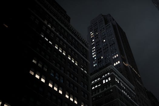 Dramatic view of illuminated skyscrapers in a city at night, showcasing urban architecture.