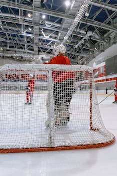 Ice hockey goalie standing behind the net, ready to defend during an indoor game.