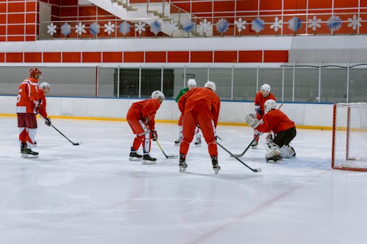 Group of hockey players practicing on an indoor ice rink, focusing on teamwork and strategy.