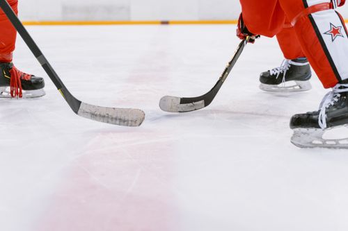 Free Intense close-up action of ice hockey players competing indoors, focusing on their sticks and skates. Stock Photo