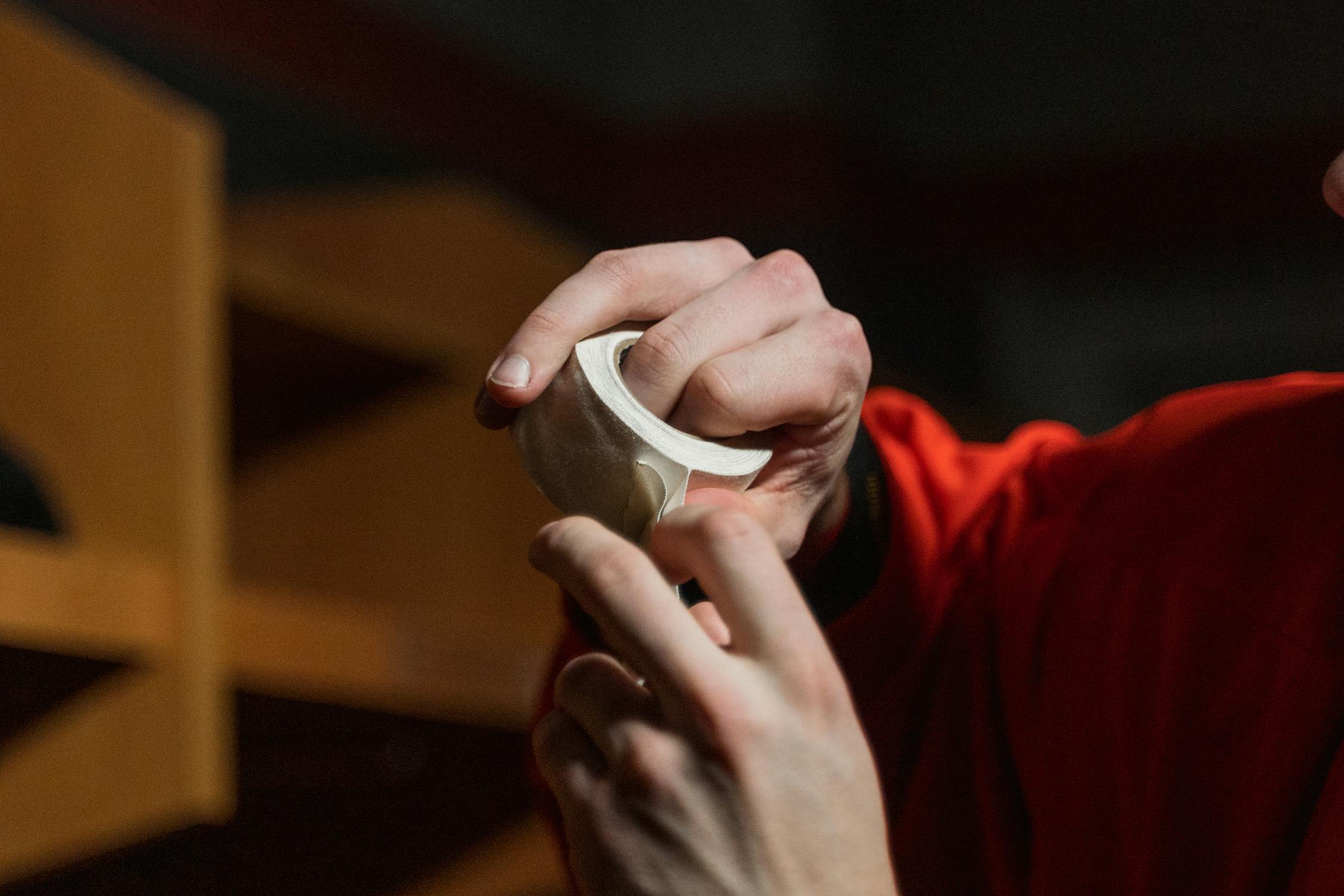 Person in Red Shirt Holding White Tape