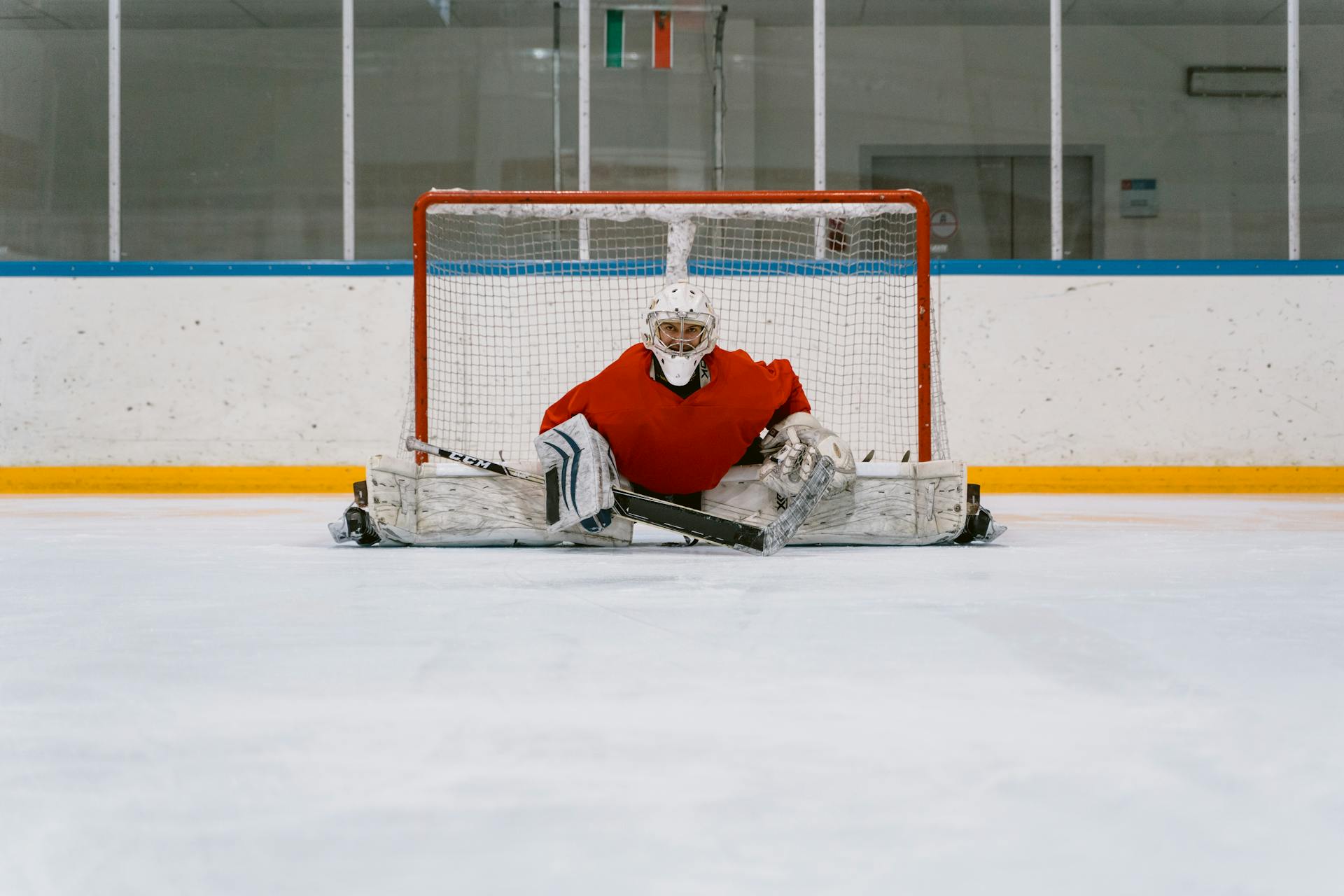 A Goaltender Doing a Split in Front of a Goal Cage