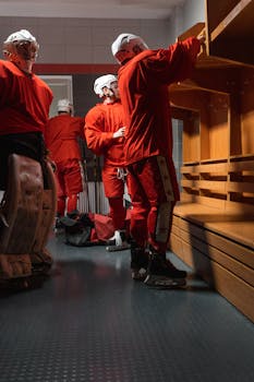 Hockey team players in red uniforms preparing in locker room.
