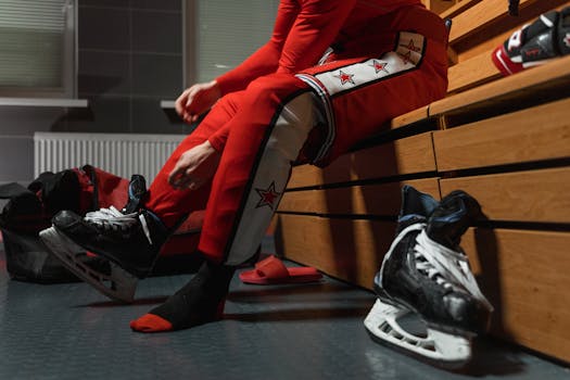 Ice hockey player wearing skates and gear in a locker room. Action-ready.