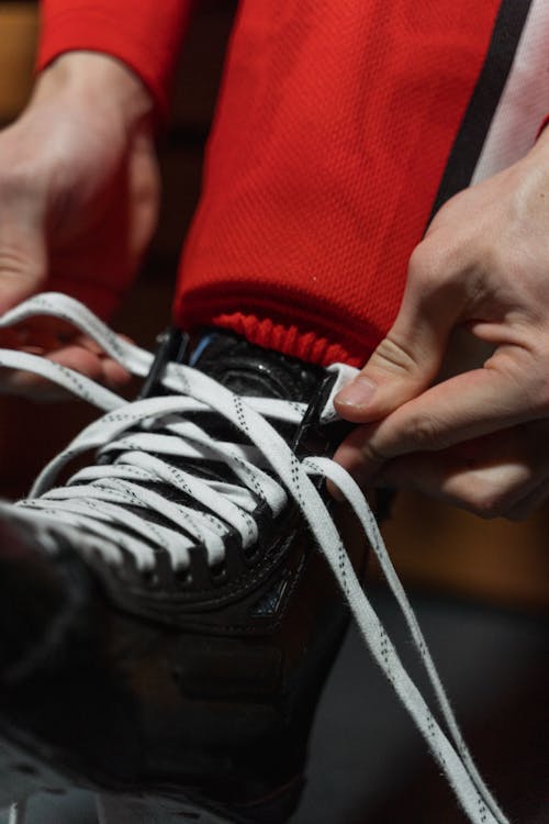 Person in Red Pants Tying Black and White Shoe Lace