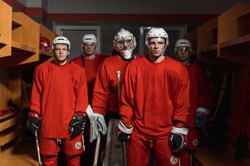 Ice Hockey Players Wearing Skullcap Standing in the Dressing Room while Looking at the Camera