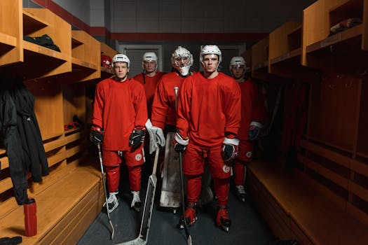 Ice hockey players in red uniforms readying up in the locker room for an intense game.