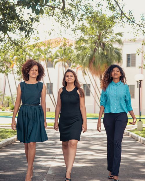 Free Three women walking confidently down a sunlit path in Sao Paulo, Brazil, showcasing friendship and fashion. Stock Photo