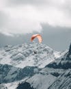 Paraglider flying over snowy mountains