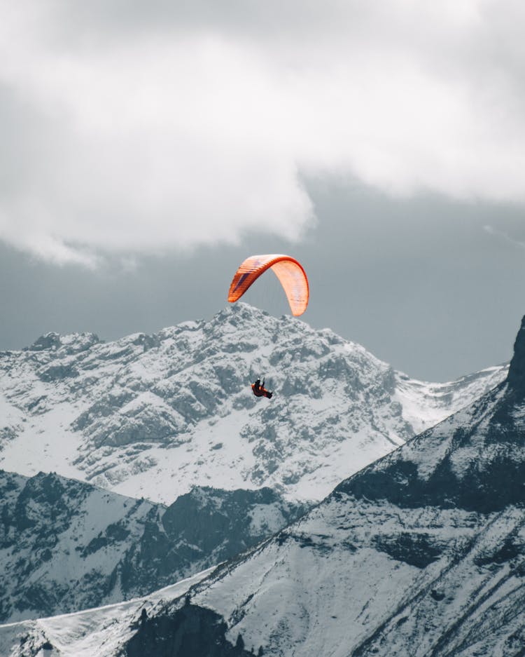 Paraglider Flying Over Snowy Mountains