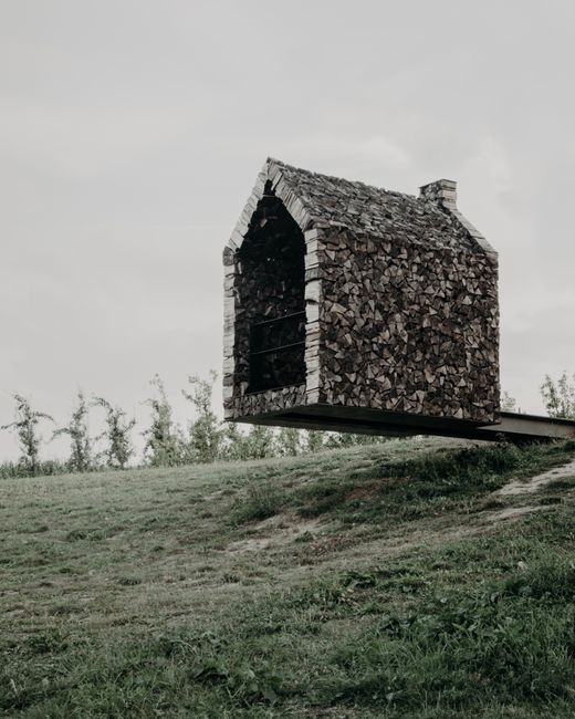 Floating chapel made of wood located near grassy meadow with plants against gray sky in countryside of Belgium in Borgloon