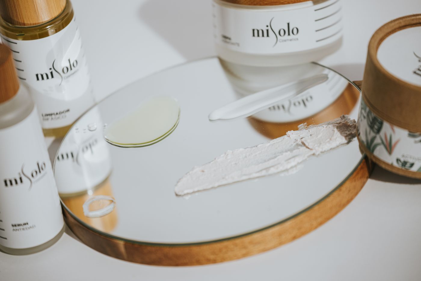 Produits cosmétiques disposés sur un plateau miroir, lumière naturelle