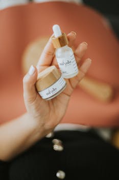 A close-up shot of a hand holding natural beauty products with a blurred background, emphasizing skincare and cosmetics.