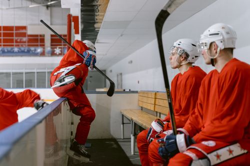 Free Ice hockey players in red uniforms sit and prepare on a rink bench. Stock Photo