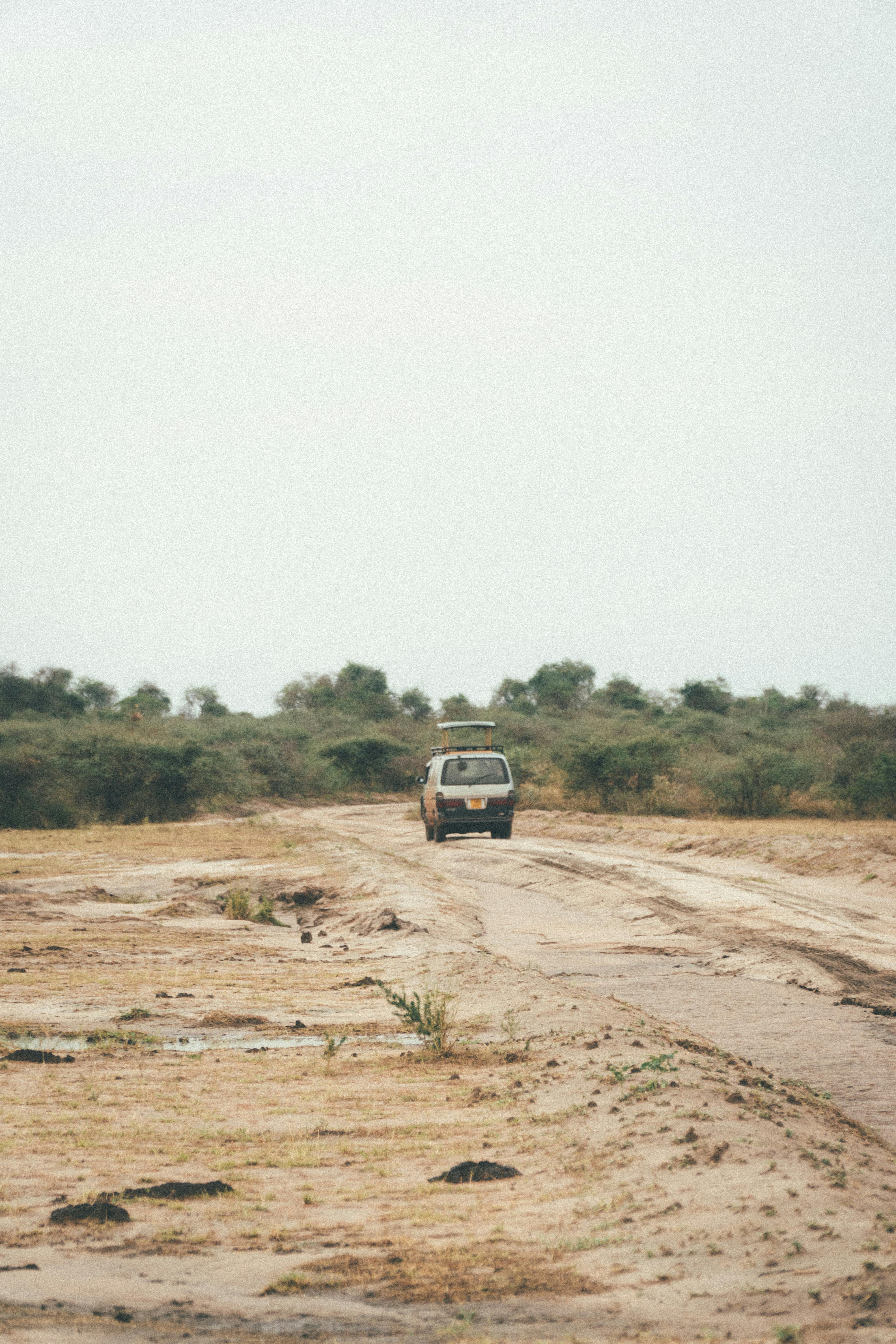 A car traveling on a dusty road in a desert setting, perfect for adventure themes.