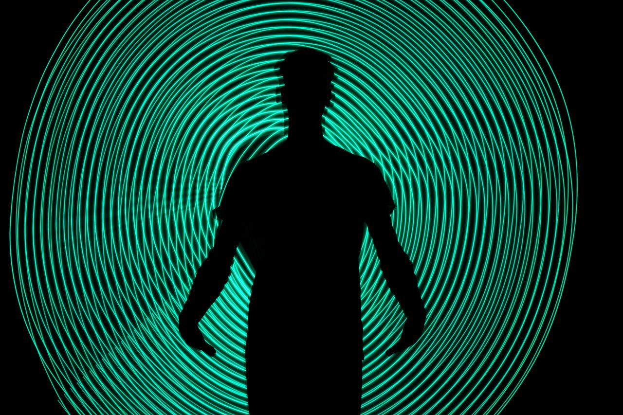 silhouette of a man standing against dynamic green light swirls captiv