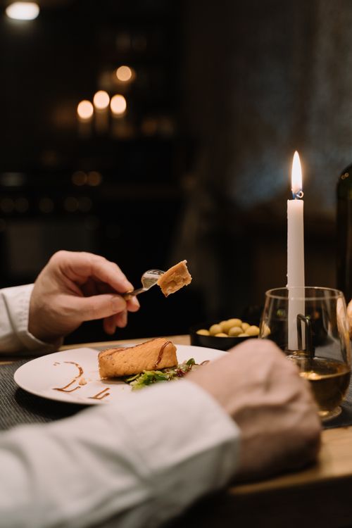 Free Close-up of a hands-on dining experience with candlelight ambiance and gourmet dish. Stock Photo