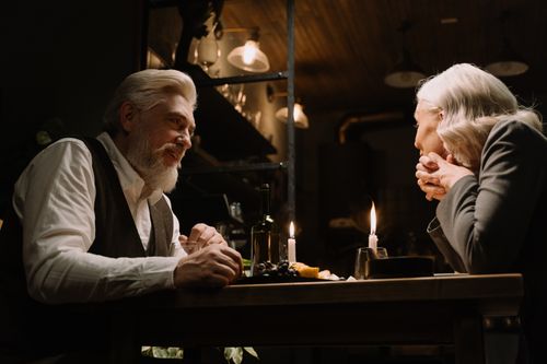 Free Elderly couple sharing a romantic candlelit dinner, creating a warm, intimate atmosphere. Stock Photo