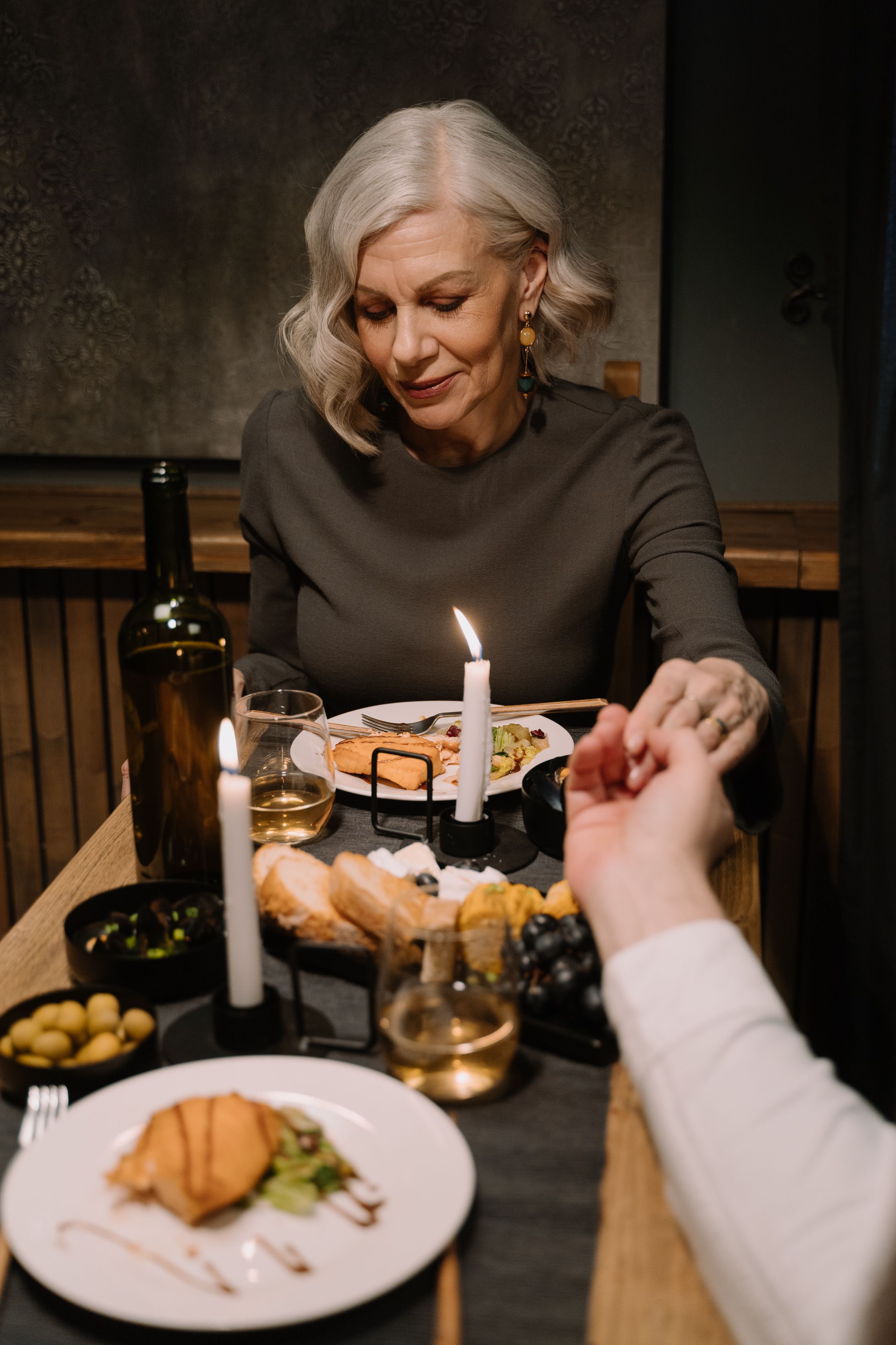 Elderly couple enjoying a romantic candlelit dinner, holding hands.
