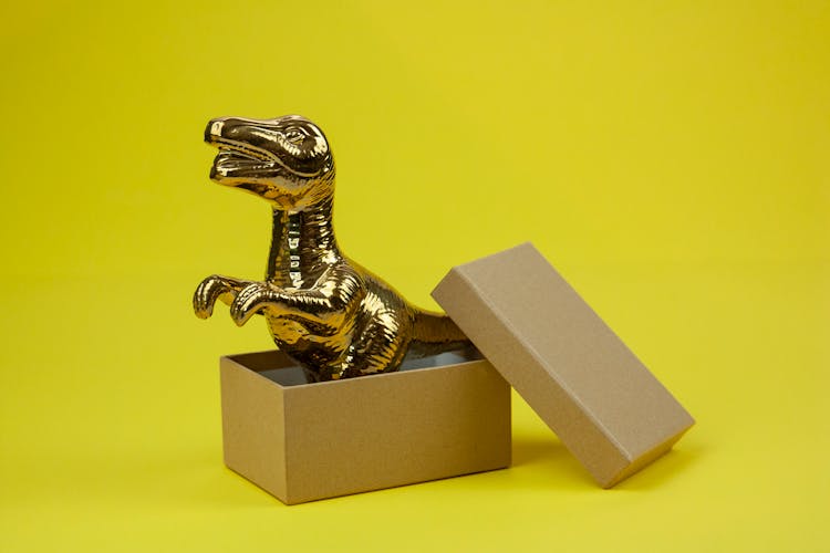 Gold Dinosaur Figurine On Brown Box