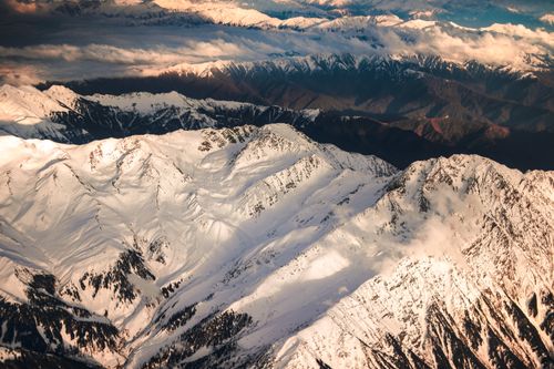 Free Aerial view of snow-covered mountain peaks in winter, capturing the majestic landscape and cold atmosphere. Stock Photo