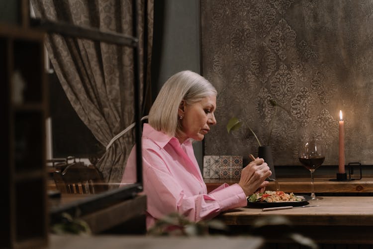 Woman In Pink Long Sleeves Eating Dinner Alone