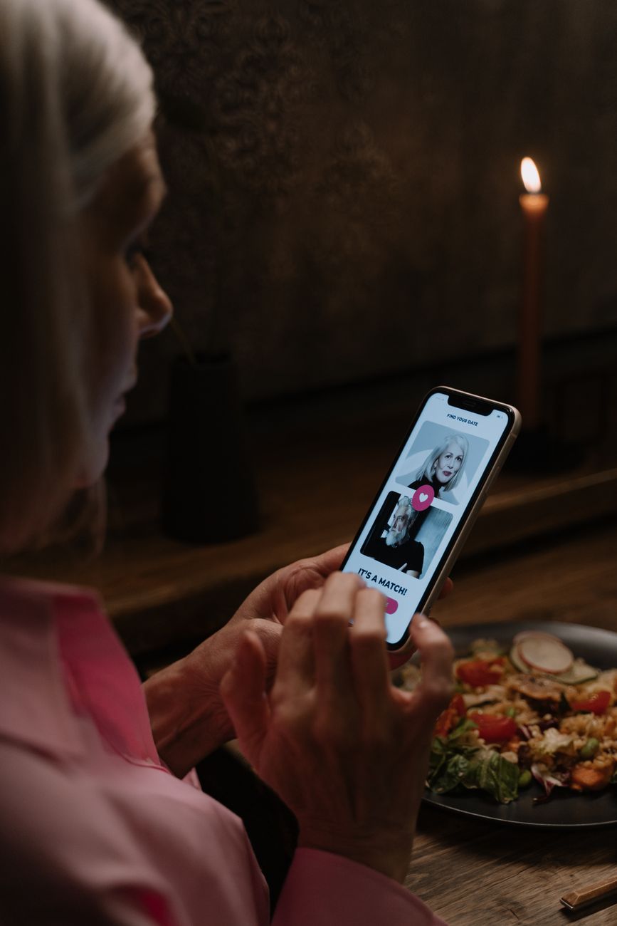 Oudere vrouw verkent een datingapp tijdens een gezellige diner.