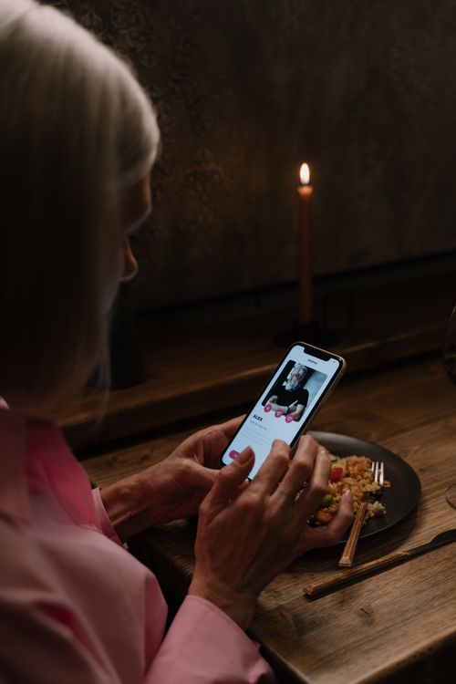Free Elderly woman using dating app on smartphone, dining table. Stock Photo