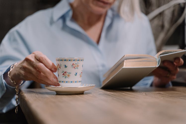 A Woman Having Coffee While Reading A Book