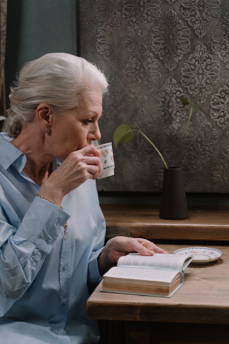 A Woman Sipping Tea While Reading A Book 