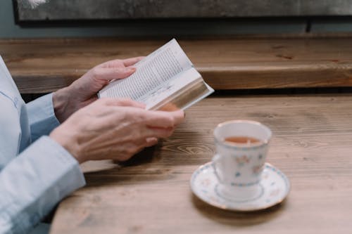 Free Person Reading a Book While Having Tea Stock Photo