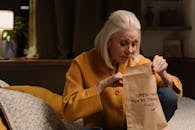 A Woman Peeking Inside a Paper Bag