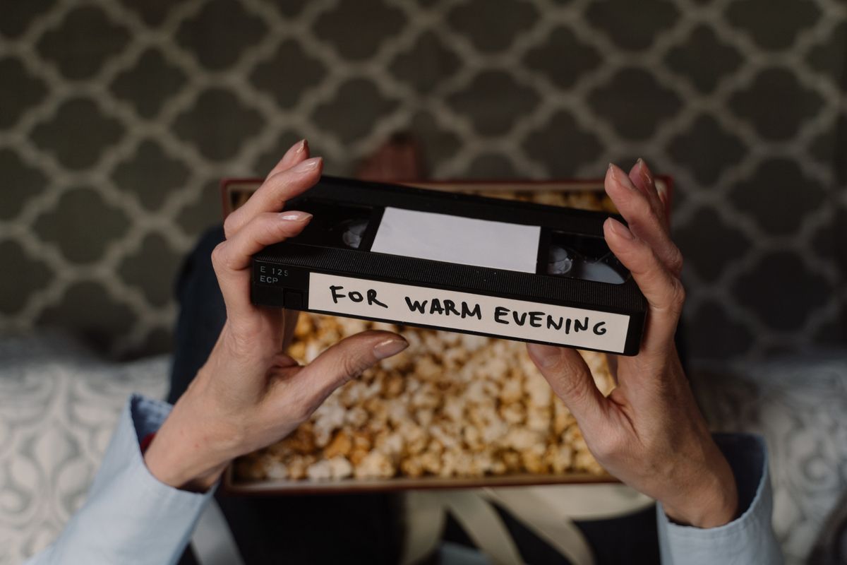Hands holding a VHS tape with popcorn for a retro movie night party