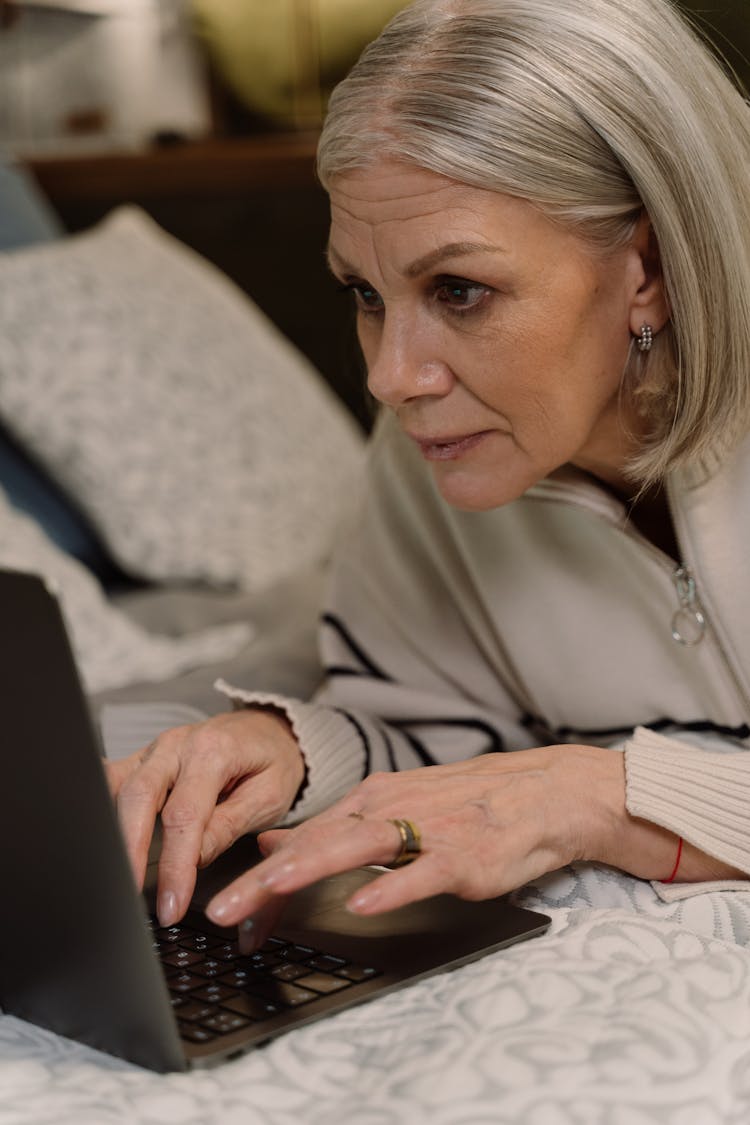 An Elderly Woman Typing On A Laptop