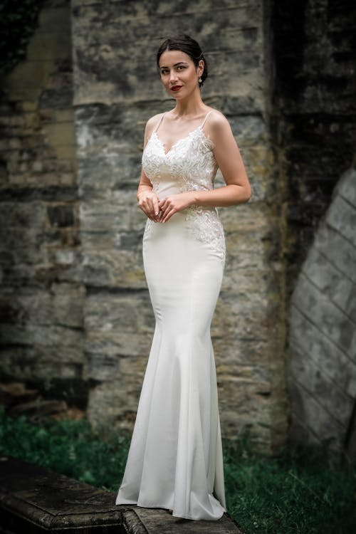 Free A Woman in White Wedding Dress Standing Near Brick Wall Stock Photo