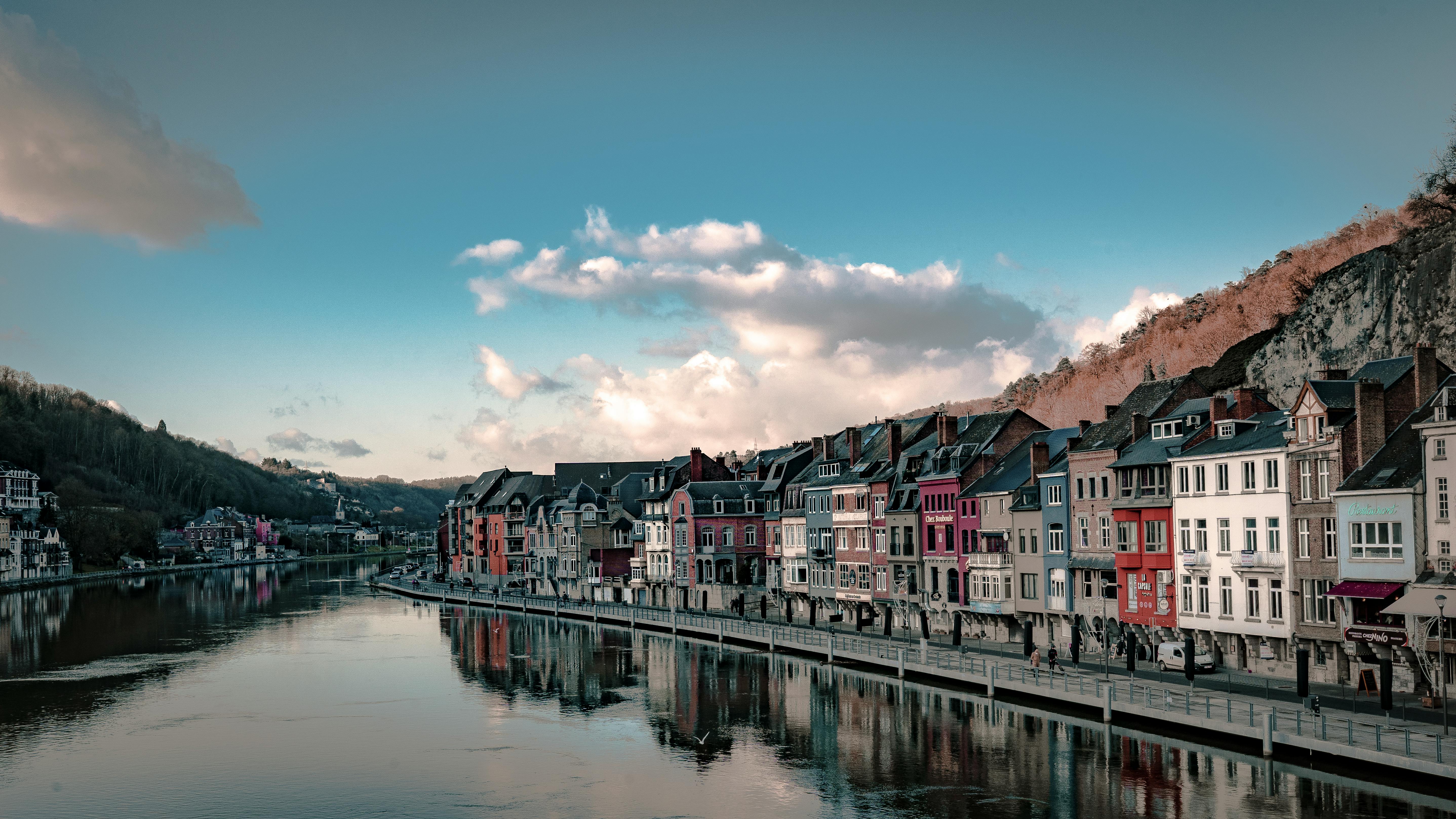 Charming riverfront view of colorful houses in Dinant, Belgium, reflecting in the Meuse River.
