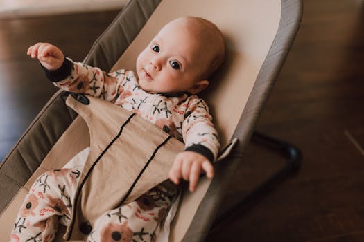 Cute baby in a patterned onesie sitting in a cozy rocker chair indoors.