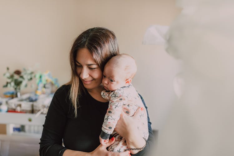 Woman In Black Long Sleeves Carrying Baby In White And Blue Onesie