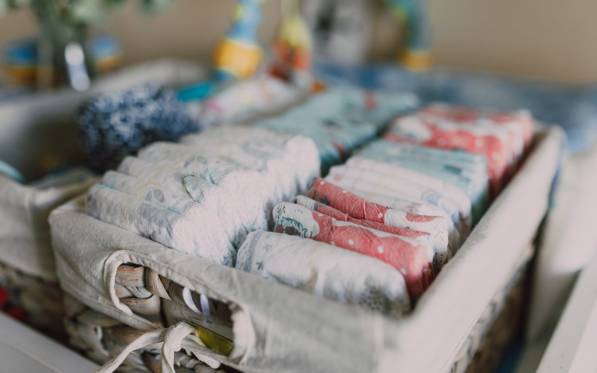 Close-up of neatly arranged colorful baby diapers in a woven basket, ideal for nursery organization.
