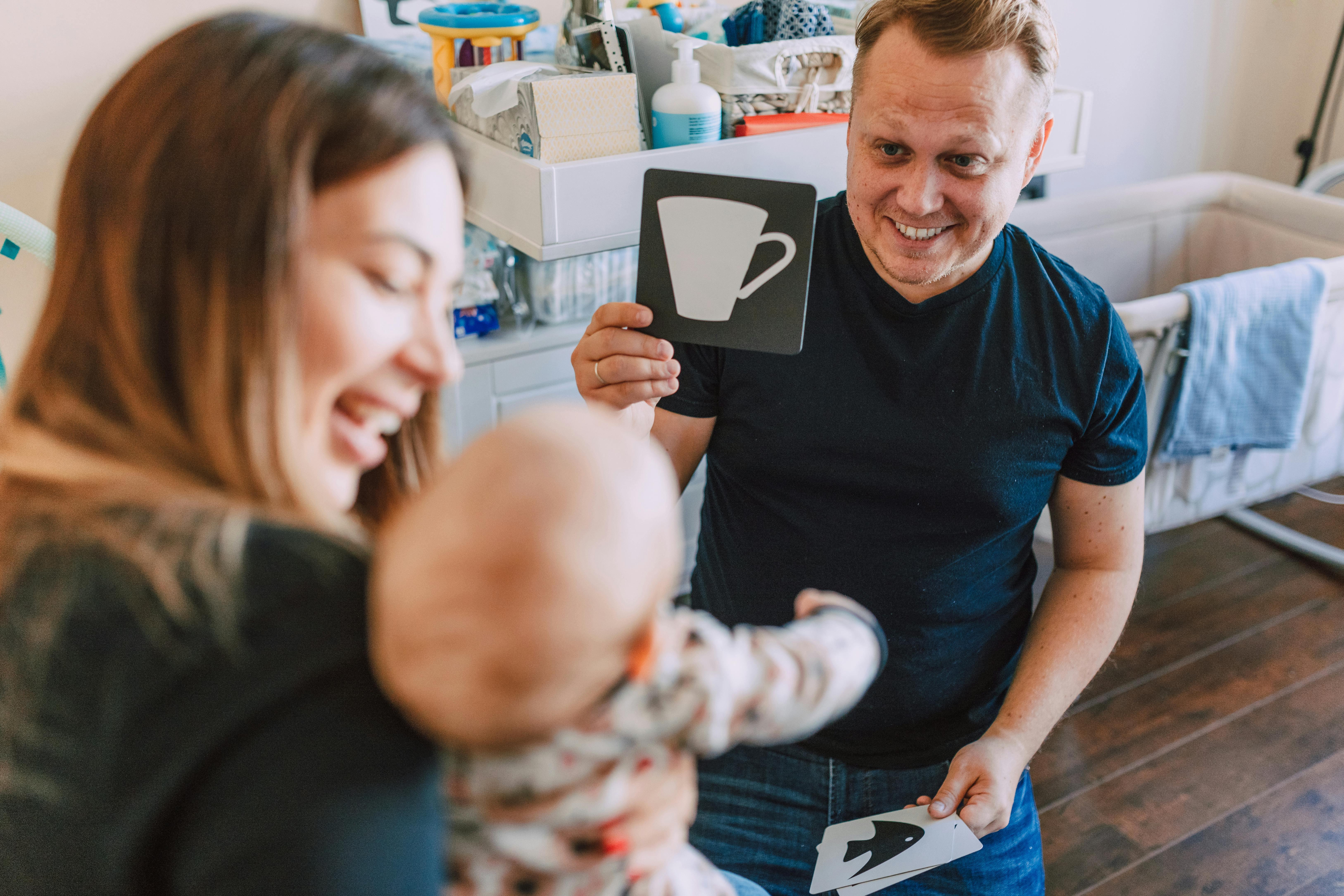 man entertaining the baby by showing learning flash cards