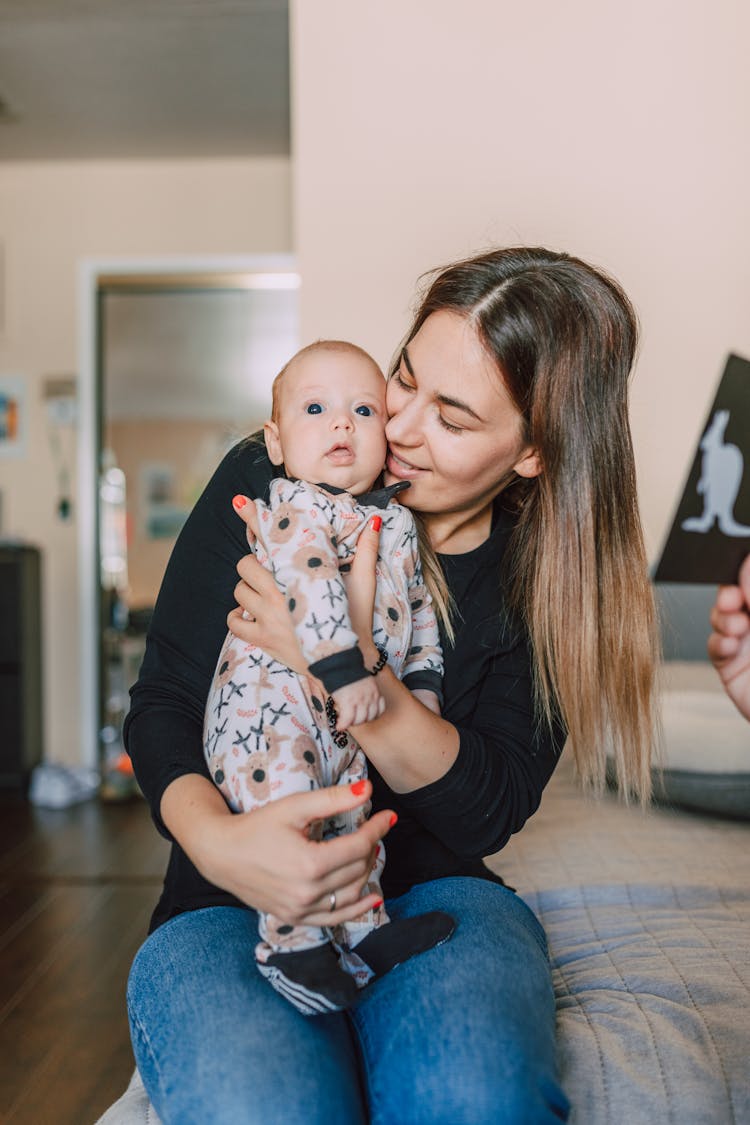 A Woman In Black Sweatshirt Sitting While Carrying Her Baby