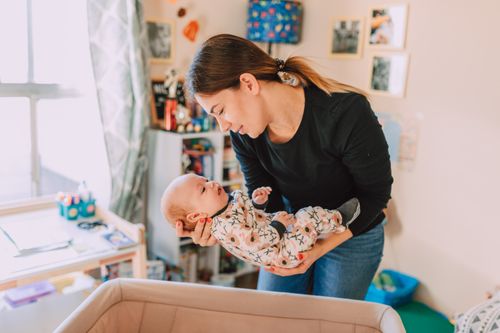 Free A mother lovingly holds her newborn baby in a cozy nursery, symbolizing motherhood and togetherness. Stock Photo