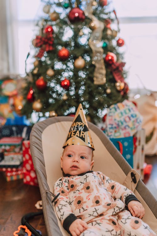 A Cute Baby in Onesie while Wearing a Party Hat