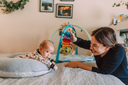 Free A joyful mother playing with her baby on the bed in a warm, cozy bedroom setting. Stock Photo