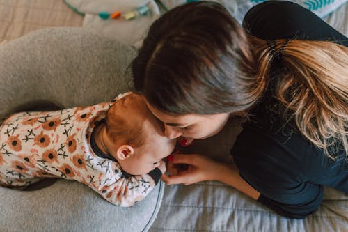 Woman in Black Long Sleeve Shirt Lying Close to Her Baby